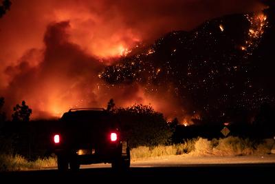 The Lytton fire: a car escapes against a background of darkness and flame.