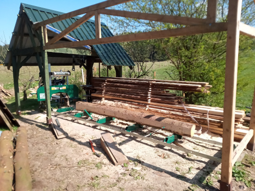 My sawmill, with a partially sawn log on the bed, and a stack of freshly sawn timber alongside.