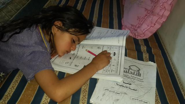 A small girl who seems to have fallen asleep while writing her homework