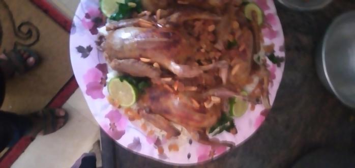 A dish of cooked pigeon meat, with nuts and slices of lime.