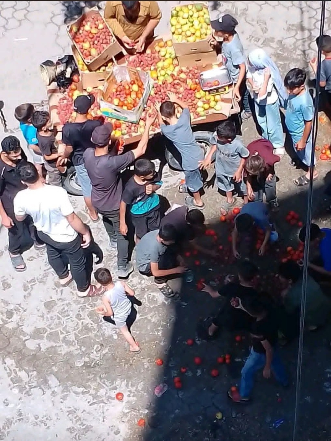 Children replacing fallen fruit on a street vendor's cart