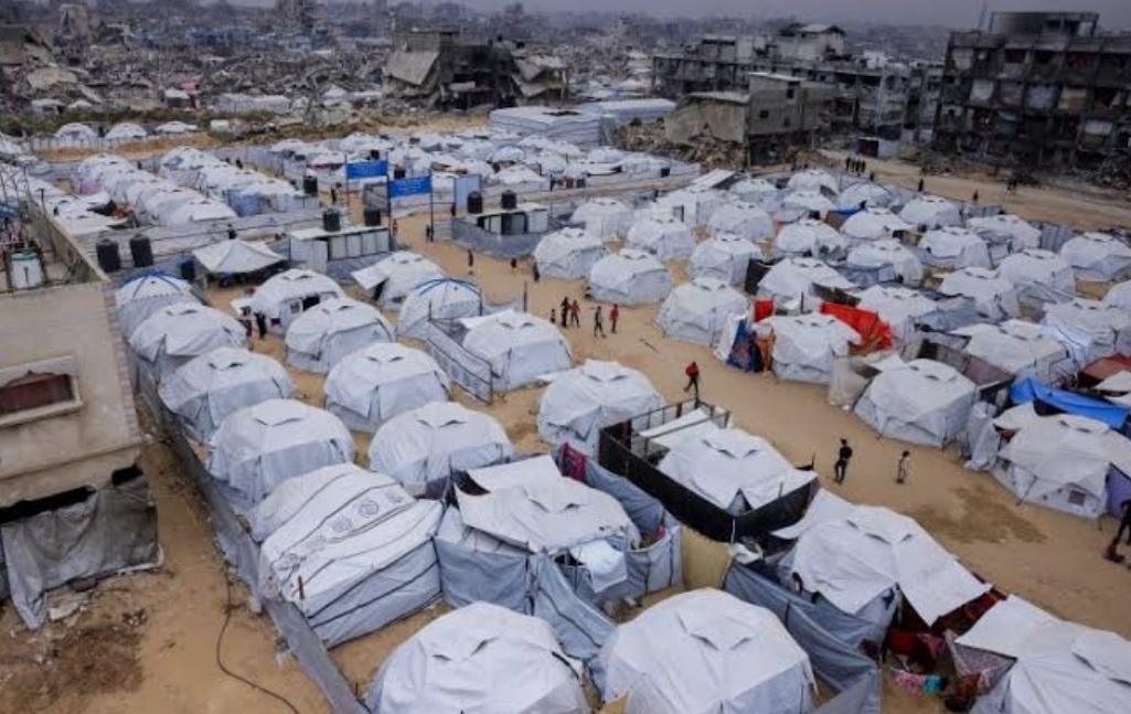 Rows of white tents, crowded closely together, on sand