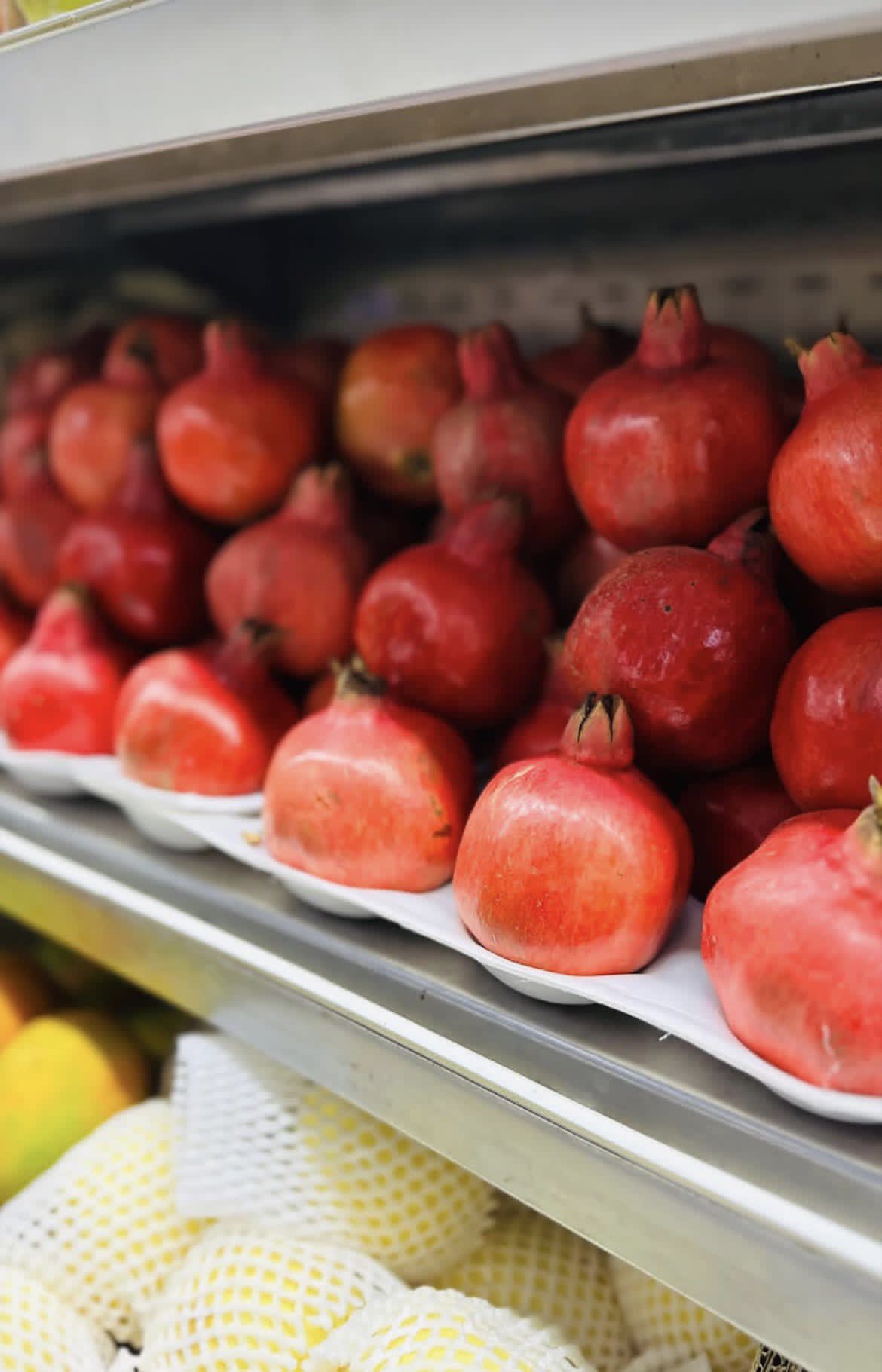 Pomegranates, pears and lemons laid out on shelves
