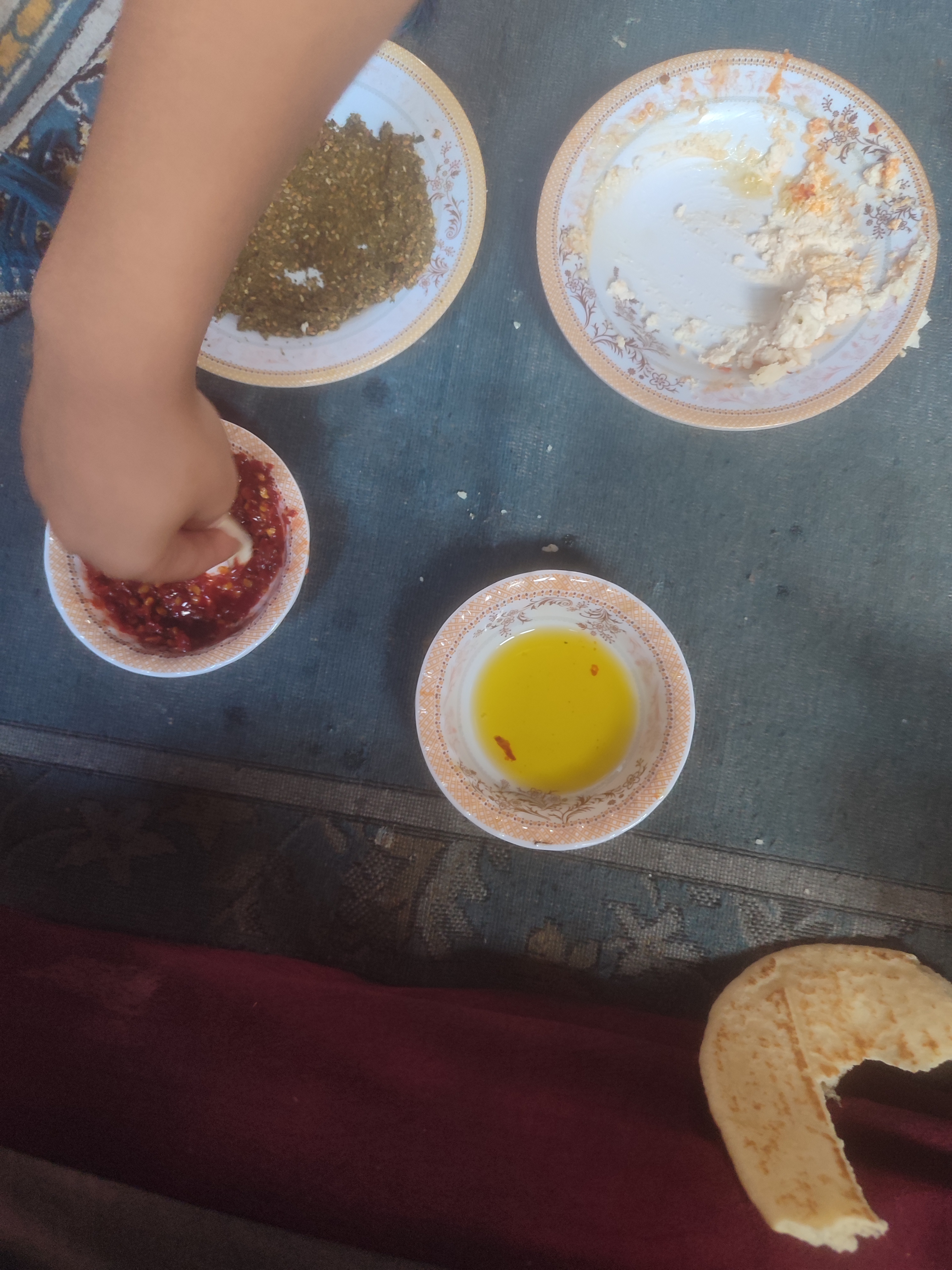 a hand dips a scrap of flat bread into a small bowl of soource